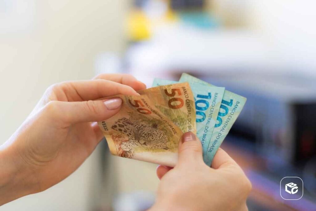 Mãos segurando notas de R$ 50 e R$ 100, representando precatórios e RPVs.